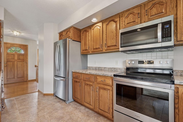 2771 County Line Ave, Osceola, WI 54020 - kitchen with stainless steel appliances, brown cabinets, light countertops, and a textured ceiling