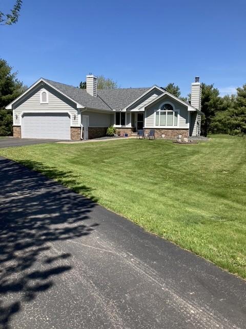 2771 County Line Ave, Osceola, WI 54020 - ranch-style home with a garage, brick siding, a chimney, and a front lawn