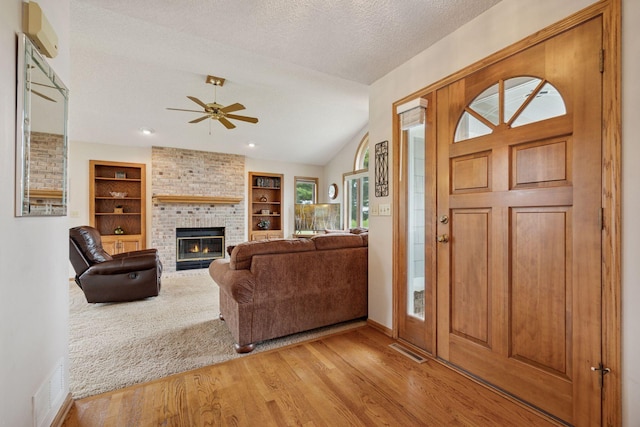 2771 County Line Ave, Osceola, WI 54020 - entrance foyer featuring a textured ceiling, light wood-style floors, a ceiling fan, lofted ceiling, and a brick fireplace