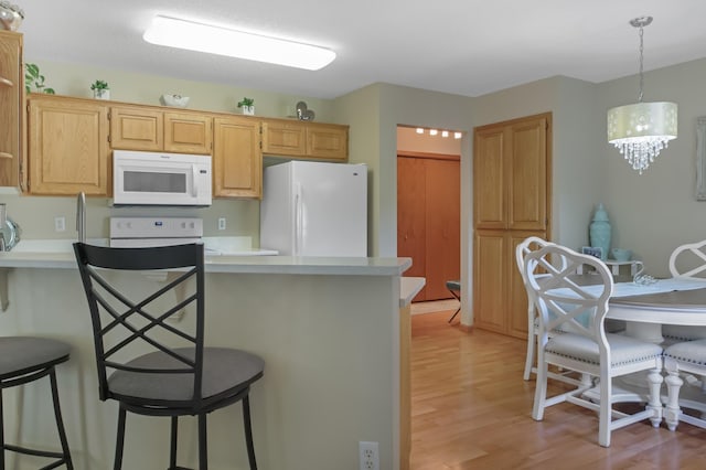 18566 Gladstone Blvd N, Maple Grove, MN 55311 - kitchen with white appliances, light wood-type flooring, a kitchen bar, a peninsula, and light countertops