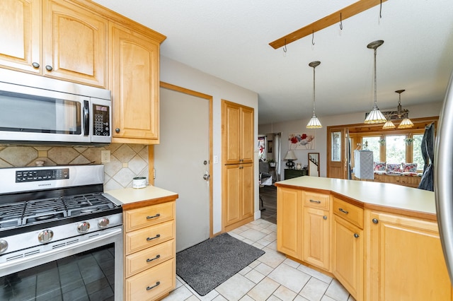 510 24th St SW, Rochester, MN 55902 - kitchen featuring appliances with stainless steel finishes, light countertops, backsplash, light tile patterned floors, and hanging light fixtures