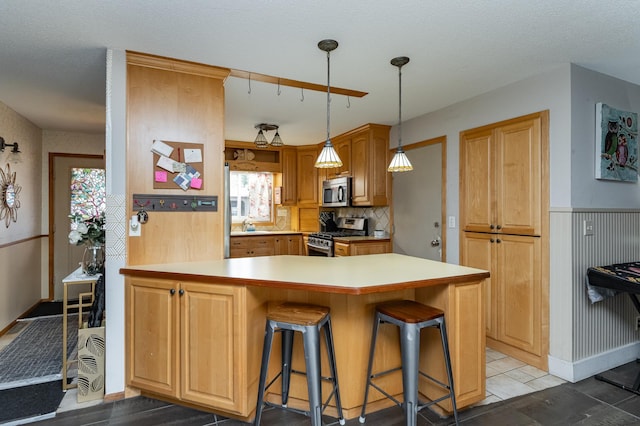 510 24th St SW, Rochester, MN 55902 - kitchen featuring appliances with stainless steel finishes, a kitchen breakfast bar, a peninsula, light countertops, and decorative light fixtures