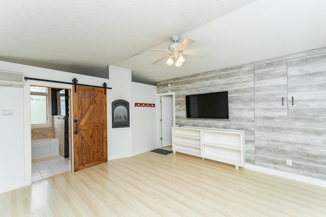 510 24th St SW, Rochester, MN 55902 - unfurnished living room featuring a barn door, a ceiling fan, wood finished floors, a wall unit AC, and an accent wall