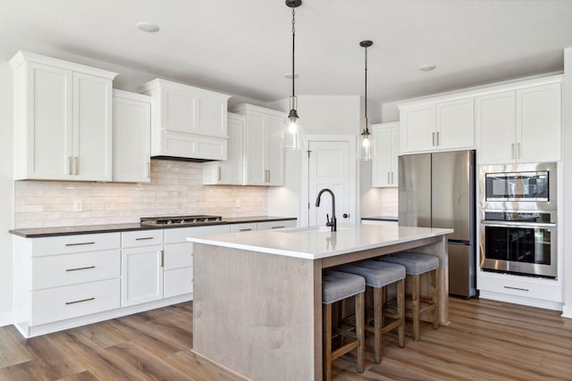 10180 Shadyview Ln N, Maple Grove, MN 55311 - kitchen with appliances with stainless steel finishes, wood finished floors, a breakfast bar, and tasteful backsplash