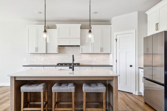 10180 Shadyview Ln N, Maple Grove, MN 55311 - kitchen with appliances with stainless steel finishes, wood finished floors, a breakfast bar, tasteful backsplash, and decorative light fixtures