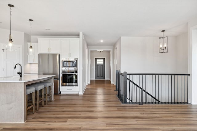 10180 Shadyview Ln N, Maple Grove, MN 55311 - kitchen featuring appliances with stainless steel finishes, light wood-style floors, white cabinets, a breakfast bar area, and light countertops