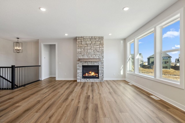 10180 Shadyview Ln N, Maple Grove, MN 55311 - unfurnished living room featuring a chandelier, light wood finished floors, recessed lighting, and a stone fireplace