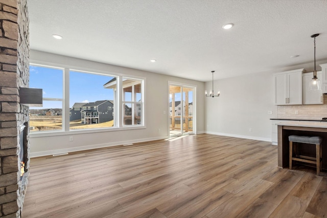 10180 Shadyview Ln N, Maple Grove, MN 55311 - unfurnished living room with a chandelier, light wood-style floors, a fireplace, a textured ceiling, and recessed lighting