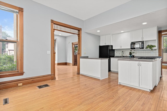 1813 11th Ave S, Minneapolis, MN 55404 - kitchen featuring black appliances, white cabinets, dark countertops, tasteful backsplash, and light wood finished floors