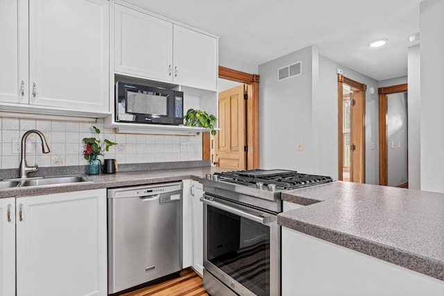 1813 11th Ave S, Minneapolis, MN 55404 - kitchen with appliances with stainless steel finishes, white cabinets, decorative backsplash, and light wood-type flooring
