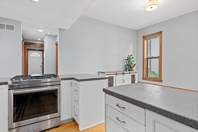 1813 11th Ave S, Minneapolis, MN 55404 - kitchen with stainless steel gas range oven, dark countertops, light wood-style flooring, white cabinets, and recessed lighting