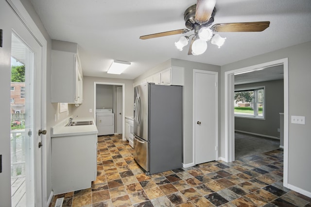 455 Sylvan St, Owatonna, MN 55060 - kitchen with freestanding refrigerator, washer / dryer, white cabinetry, a ceiling fan, and dark stone finish flooring