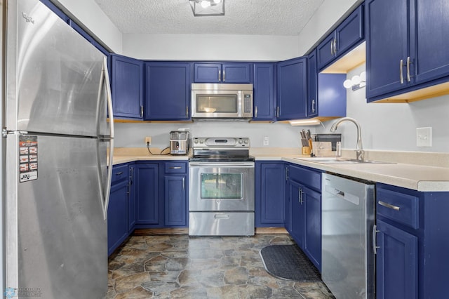 3034 18th St S, Fargo, ND 58103 - kitchen with stainless steel appliances, blue cabinets, a textured ceiling, stone finish flooring, and light countertops