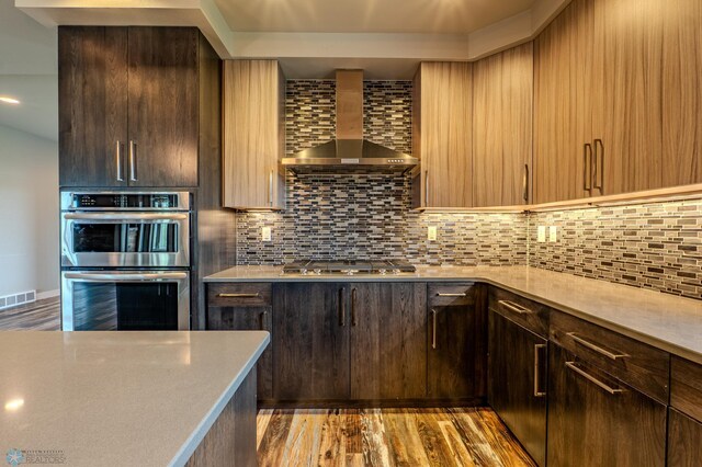 3405 4th St E, West Fargo, ND 58078 - kitchen featuring stainless steel appliances, wall chimney range hood, light wood-style flooring, light countertops, and tasteful backsplash