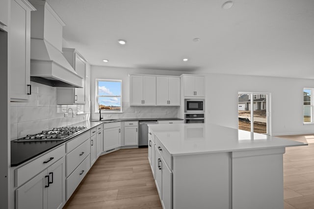 11532 Polaris Ln N, Dayton, MN 55369 - kitchen with appliances with stainless steel finishes, premium range hood, a kitchen island, recessed lighting, and white cabinetry