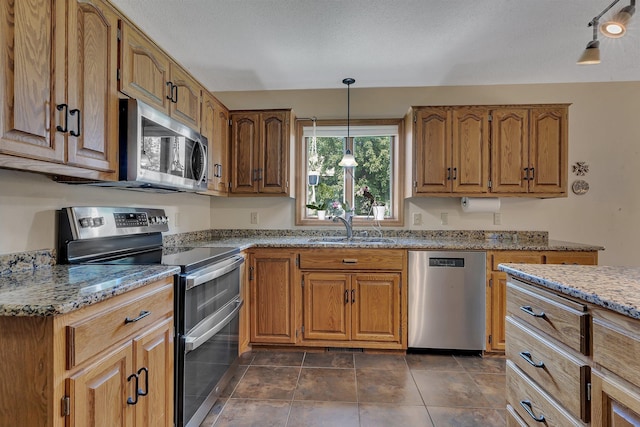2708 Tranquility Dr, Saint Cloud, MN 56301 - kitchen featuring appliances with stainless steel finishes, light stone countertops, decorative light fixtures, and brown cabinetry