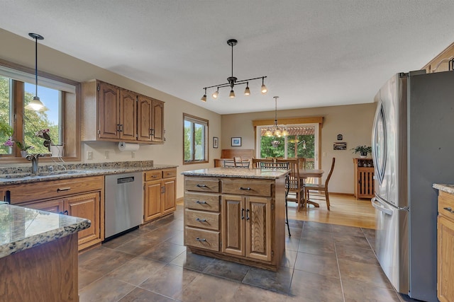 2708 Tranquility Dr, Saint Cloud, MN 56301 - kitchen with appliances with stainless steel finishes, track lighting, a center island, hanging light fixtures, and dark tile patterned flooring