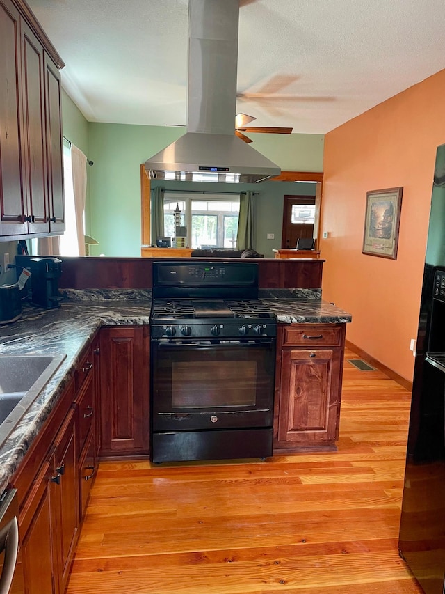 60 Main St, Kimball, MN 55353 - kitchen featuring black gas range oven, island range hood, light wood-style floors, and ceiling fan