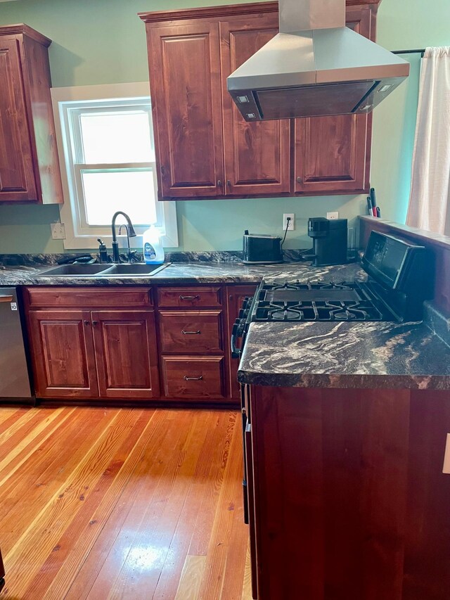 60 Main St, Kimball, MN 55353 - kitchen featuring exhaust hood, stainless steel dishwasher, dark countertops, light wood finished floors, and gas range oven
