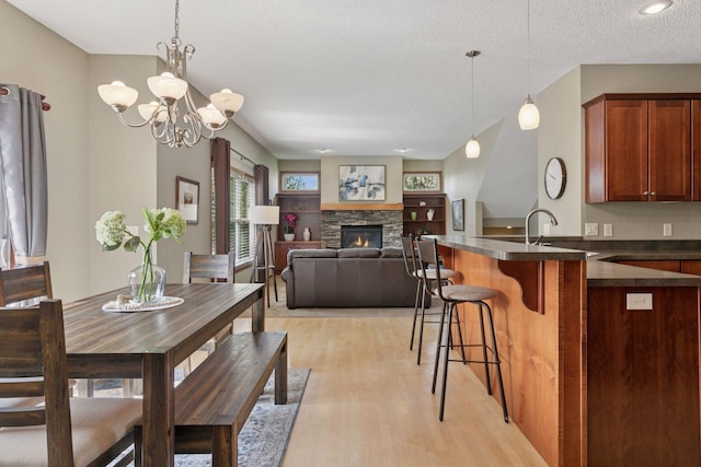 14896 Brenner Ct, Rosemount, MN 55068 - dining room with light wood-style flooring, a fireplace, a chandelier, and a textured ceiling