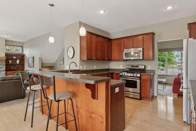 14896 Brenner Ct, Rosemount, MN 55068 - kitchen featuring stainless steel appliances, open floor plan, dark countertops, light wood-style flooring, and a textured ceiling