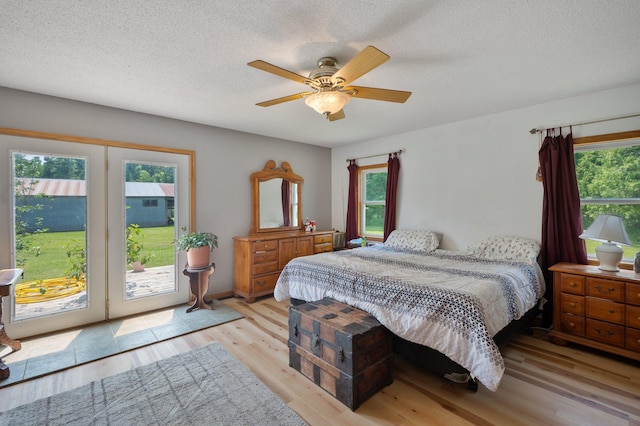 8241 120th St, Bogus Brook Twp, MN 56353 - bedroom featuring access to exterior, light wood-style floors, multiple windows, a textured ceiling, and ceiling fan