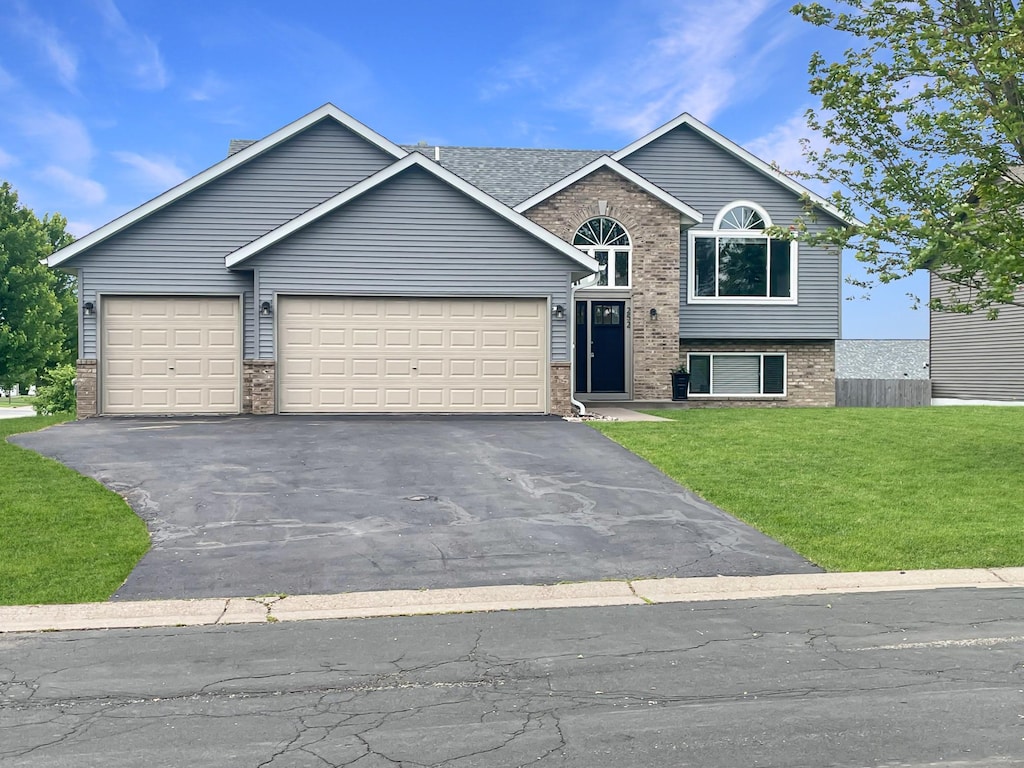 252 Birch St, Baldwin, WI 54002 - view of front of property featuring brick siding, a garage, a front yard, and driveway