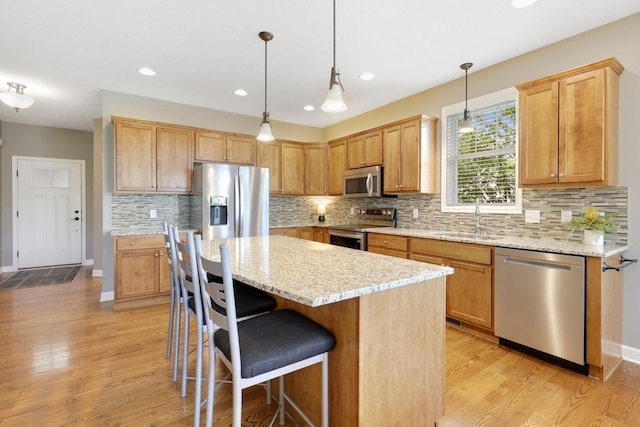 kitchen featuring appliances with stainless steel finishes, a center island, light wood-style floors, backsplash, and recessed lighting