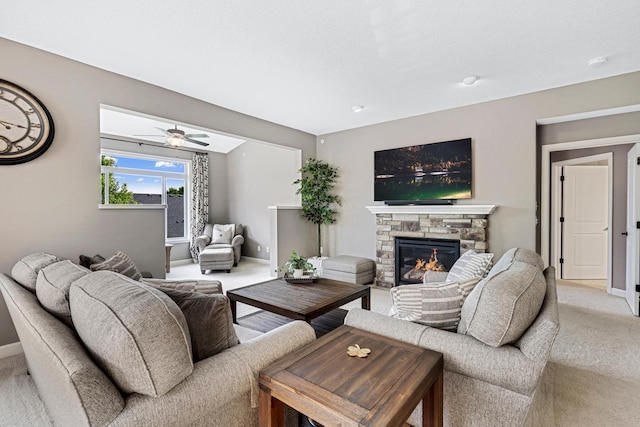 living room with light colored carpet, a stone fireplace, and a ceiling fan