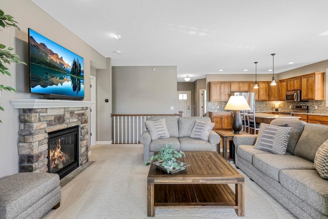 living room featuring light carpet, a stone fireplace, and recessed lighting