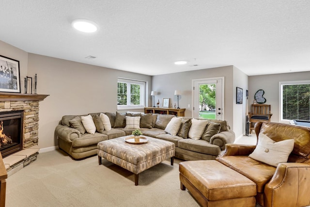 living area featuring light carpet, a stone fireplace, and a textured ceiling