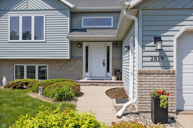 2819 33rd St S, Fargo, ND 58103 - view of exterior entry with an attached garage, brick siding, and a shingled roof