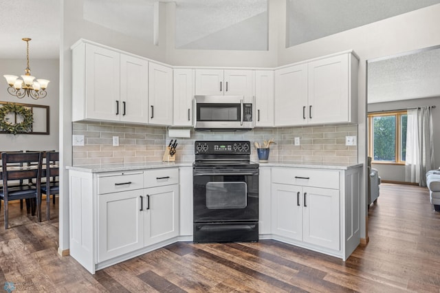 2819 33rd St S, Fargo, ND 58103 - kitchen featuring stainless steel microwave, electric range, a chandelier, dark wood-style floors, and lofted ceiling