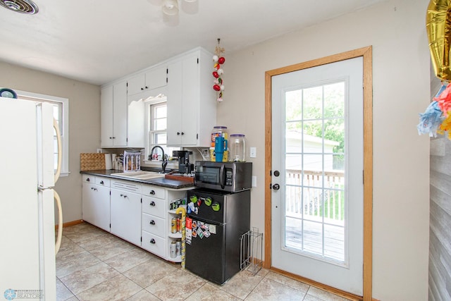 419 18th St S, Moorhead, MN 56560 - kitchen with freestanding refrigerator, stainless steel microwave, white cabinets, dark countertops, and light tile patterned flooring