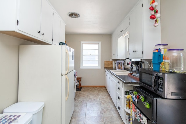 419 18th St S, Moorhead, MN 56560 - kitchen with stainless steel microwave, white cabinetry, light tile patterned floors, freestanding refrigerator, and refrigerator