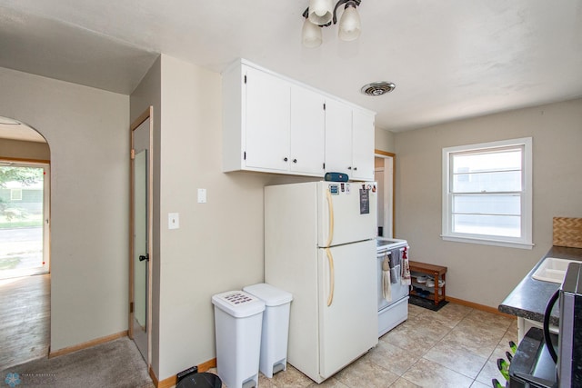 419 18th St S, Moorhead, MN 56560 - kitchen featuring white appliances, arched walkways, healthy amount of natural light, and white cabinets