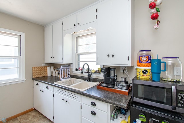 419 18th St S, Moorhead, MN 56560 - kitchen featuring stainless steel microwave, dark countertops, healthy amount of natural light, and white cabinets