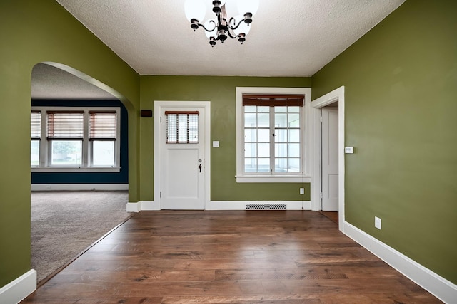 579 4th St, Winona, MN 55987 - foyer with a textured ceiling, a chandelier, dark wood-type flooring, and arched walkways