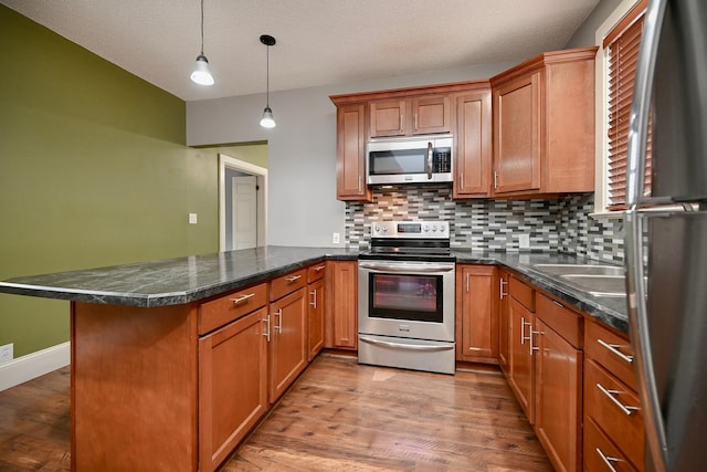 579 4th St, Winona, MN 55987 - kitchen featuring appliances with stainless steel finishes, a peninsula, decorative backsplash, and light wood finished floors