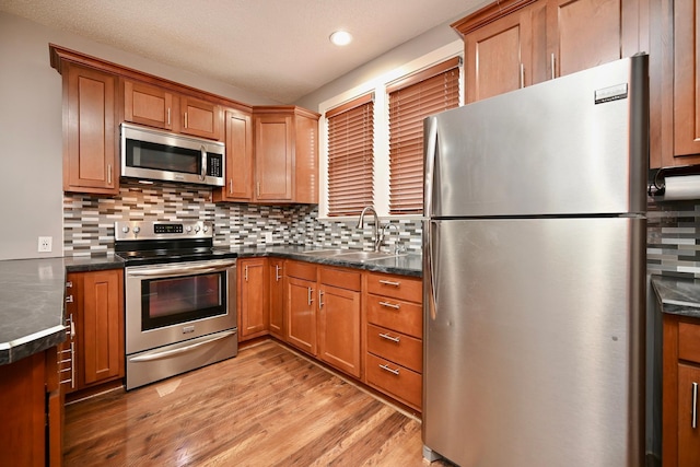 579 4th St, Winona, MN 55987 - kitchen with stainless steel appliances, light wood-style floors, decorative backsplash, brown cabinets, and recessed lighting