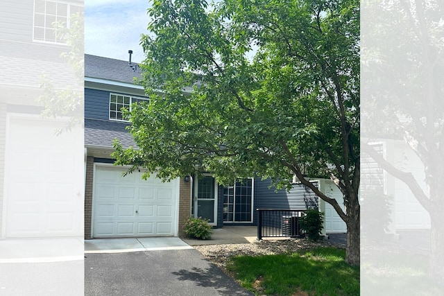 1865 Donegal Dr Unit 3, Woodbury, MN 55125 - obstructed view of property featuring roof with shingles, a garage, driveway, and brick siding