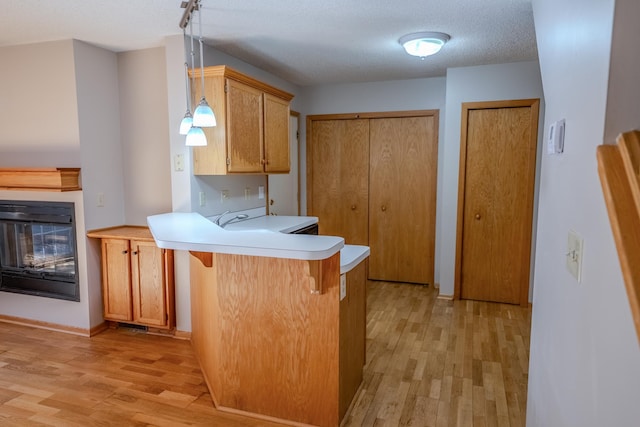1865 Donegal Dr Unit 3, Woodbury, MN 55125 - kitchen featuring light wood-type flooring, a peninsula, a kitchen breakfast bar, light countertops, and a textured ceiling
