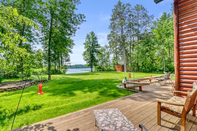 53245 Sunrise Ln, Park Rapids, MN 56470 - wooden deck featuring a water view, a storage unit, a yard, and view of wooded area