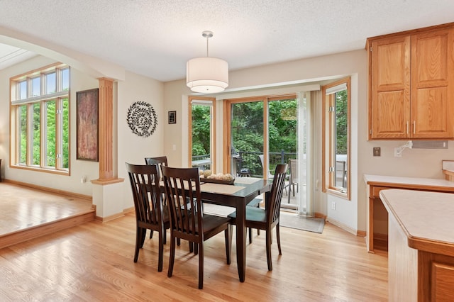 9534 Kirkwood Way N, Maple Grove, MN 55369 - dining area featuring light wood-style flooring, plenty of natural light, arched walkways, decorative columns, and a textured ceiling