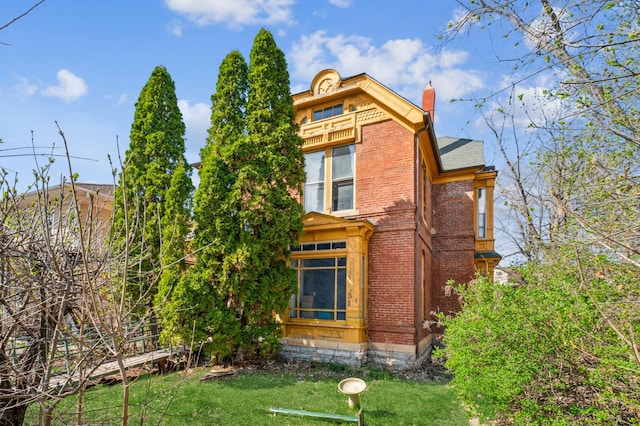 65 George St E, Saint Paul, MN 55107 - view of home's exterior featuring brick siding, a chimney, a yard, a balcony, and a sunroom