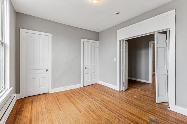 65 George St E, Saint Paul, MN 55107 - unfurnished bedroom featuring a baseboard radiator and light wood finished floors
