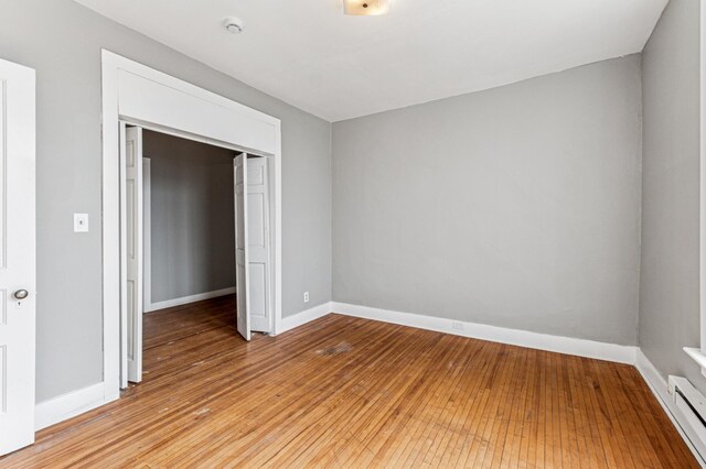 65 George St E, Saint Paul, MN 55107 - unfurnished bedroom featuring a baseboard heating unit, light wood-type flooring, and a closet