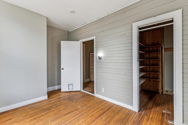 65 George St E, Saint Paul, MN 55107 - unfurnished bedroom featuring hardwood / wood-style flooring, wood walls, and a closet
