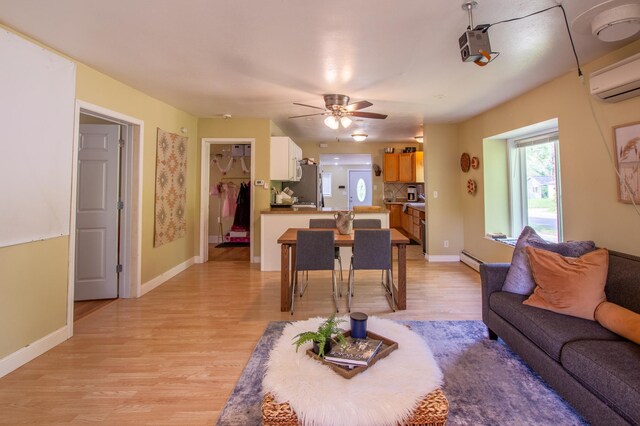 724 10th St NW, Bemidji, MN 56601 - living room featuring a wall mounted AC, light wood-style flooring, ceiling fan, and a baseboard radiator