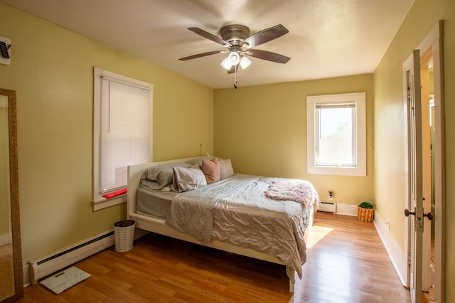 724 10th St NW, Bemidji, MN 56601 - bedroom featuring a baseboard radiator, wood finished floors, and ceiling fan